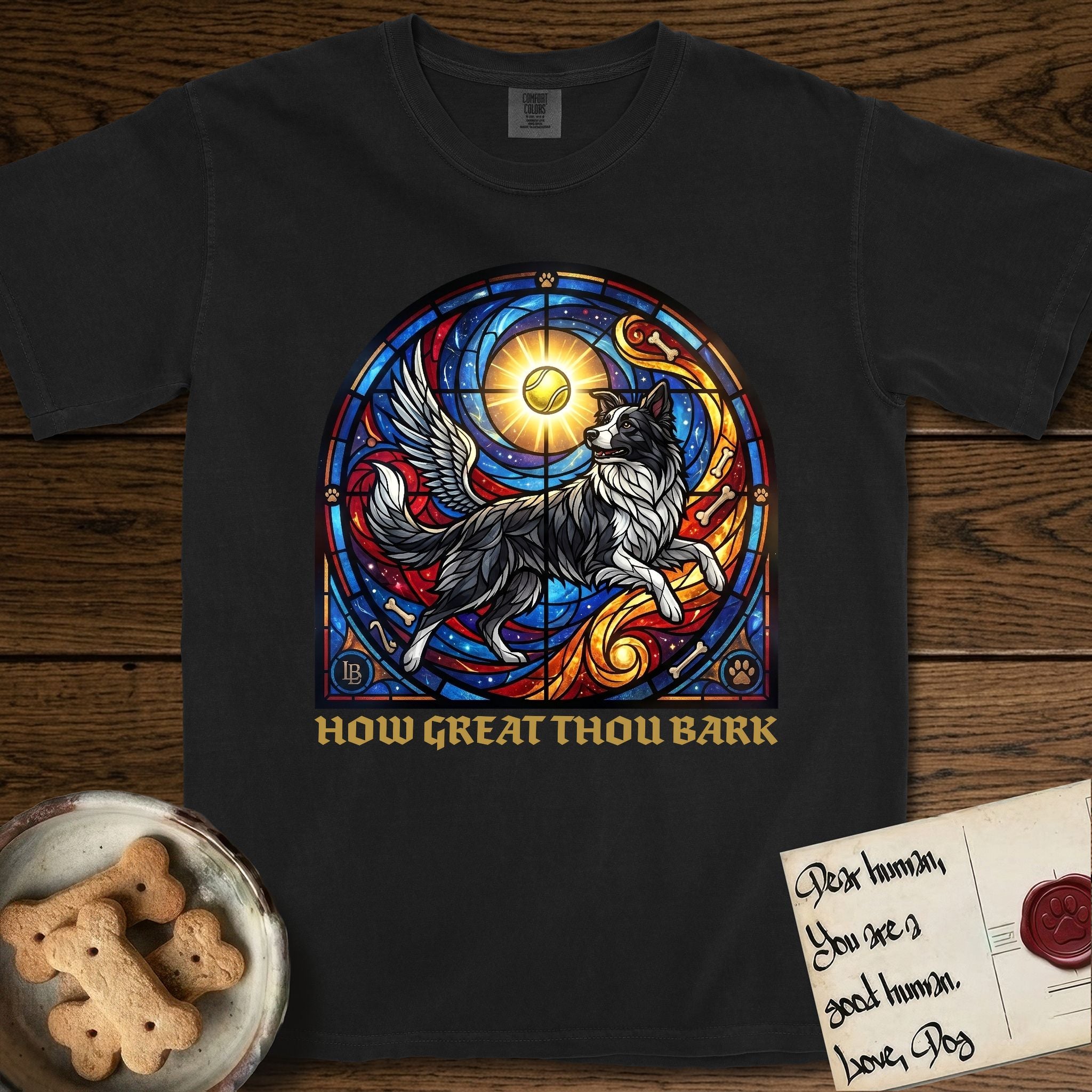 How Great Thou Bark Border Collie T-Shirt flat lay in Black, featuring a full-color stained-glass saint window of a winged Border Collie leaping after a glowing tennis ball, with a halo.