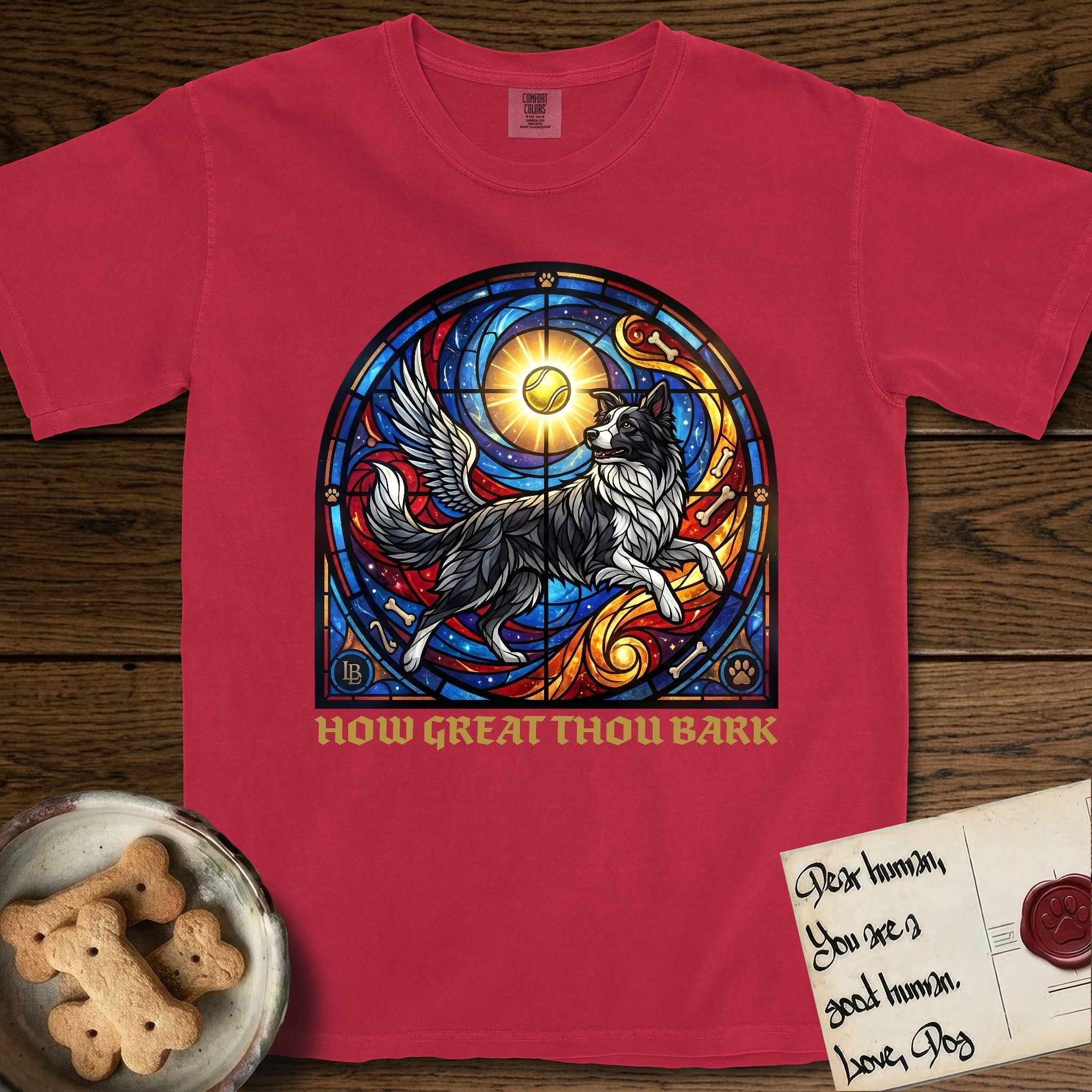 How Great Thou Bark Border Collie T-Shirt flat lay in Red, featuring a full-color stained-glass saint window of a winged Border Collie leaping after a glowing tennis ball, with a halo.