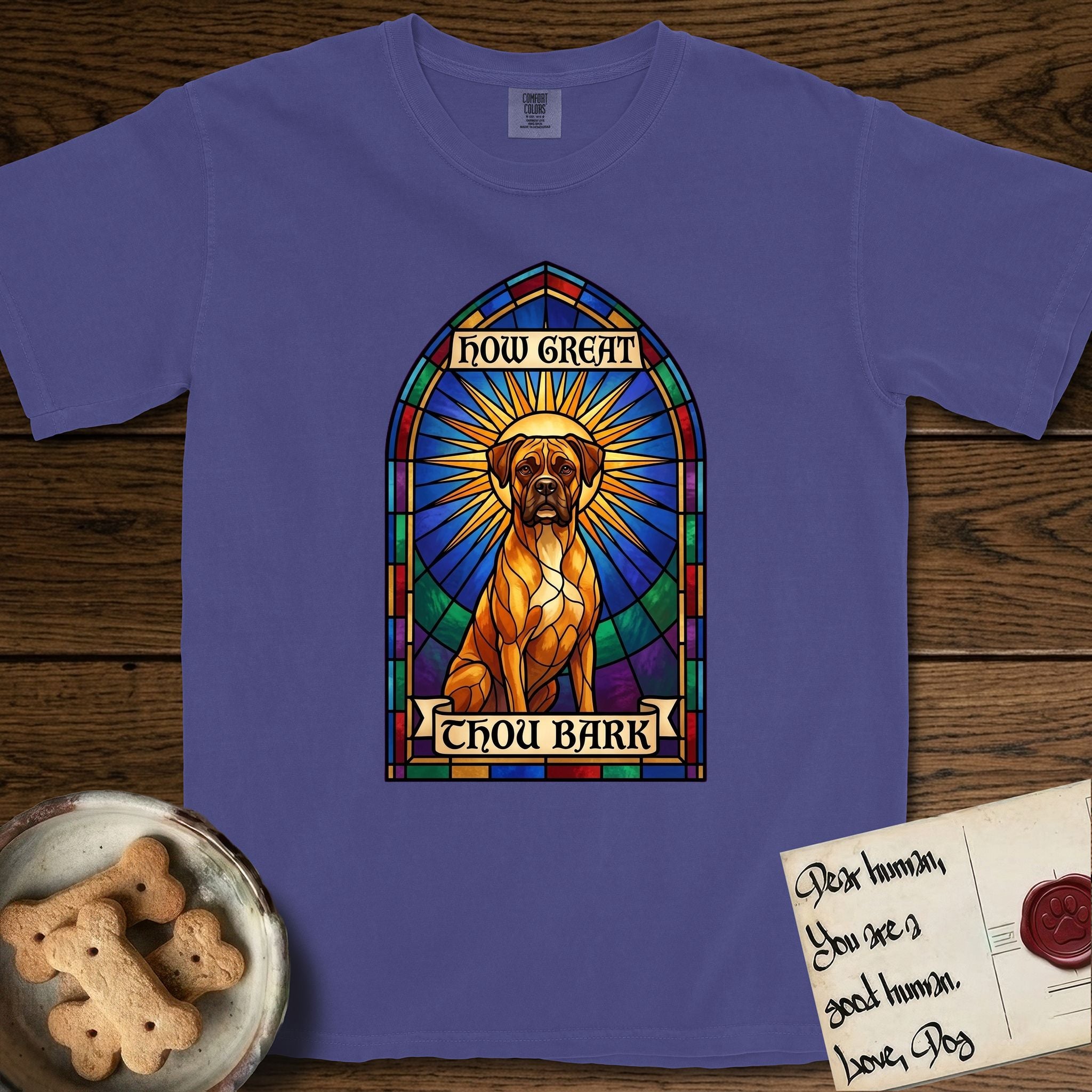 How Great Thou Bark Boxer T-Shirt flat lay in Grape, featuring a full-color stained-glass saint window of a Boxer seated in warm golden light with a halo.