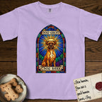 How Great Thou Bark Boxer T-Shirt flat lay in Orchid, featuring a full-color stained-glass saint window of a Boxer seated in warm golden light with a halo.