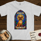 How Great Thou Bark Boxer T-Shirt flat lay in White, featuring a full-color stained-glass saint window of a Boxer seated in warm golden light with a halo.