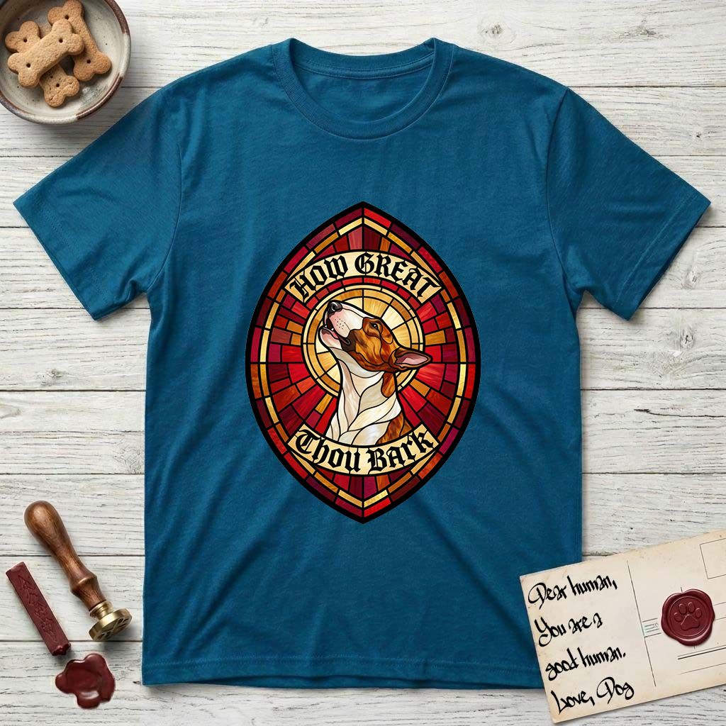 How Great Thou Bark Bull Terrier T-Shirt flat lay in Antique Sapphire, featuring a full-color stained-glass saint window of a brown and white Bull Terrier with head raised and mouth open mid-howl, haloed in golden light.