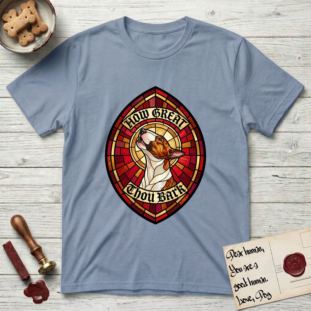 How Great Thou Bark Bull Terrier T-Shirt flat lay in Stone Blue, featuring a full-color stained-glass saint window of a brown and white Bull Terrier with head raised and mouth open mid-howl, haloed in golden light.