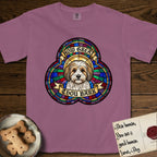 How Great Thou Bark Coton de Tulear T-Shirt flat lay in Berry, featuring a full-color stained-glass saint window of a sable and white Coton de Tulear facing forward, haloed in golden light.