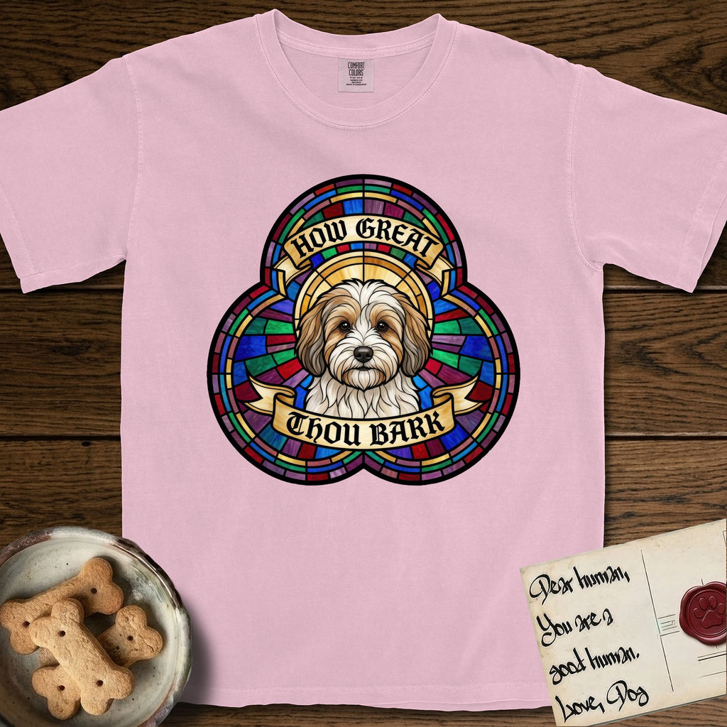 How Great Thou Bark Coton de Tulear T-Shirt flat lay in Blossom, featuring a full-color stained-glass saint window of a sable and white Coton de Tulear facing forward, haloed in golden light.