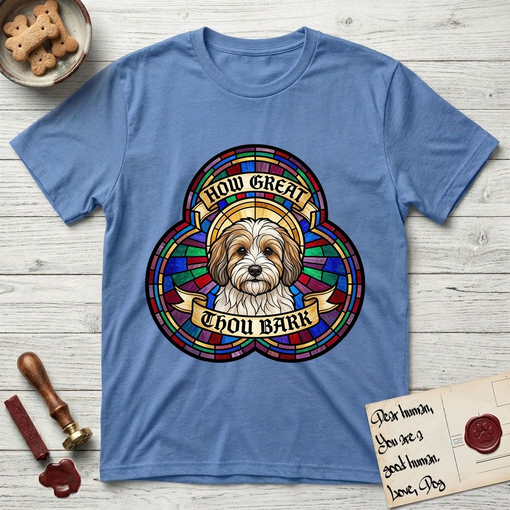 How Great Thou Bark Coton de Tulear T-Shirt flat lay in Carolina Blue, featuring a full-color stained-glass saint window of a sable and white Coton de Tulear facing forward, haloed in golden light.