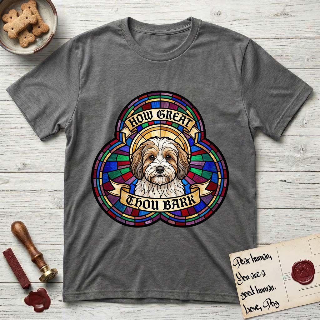 How Great Thou Bark Coton de Tulear T-Shirt flat lay in Dark Heather, featuring a full-color stained-glass saint window of a sable and white Coton de Tulear facing forward, haloed in golden light.