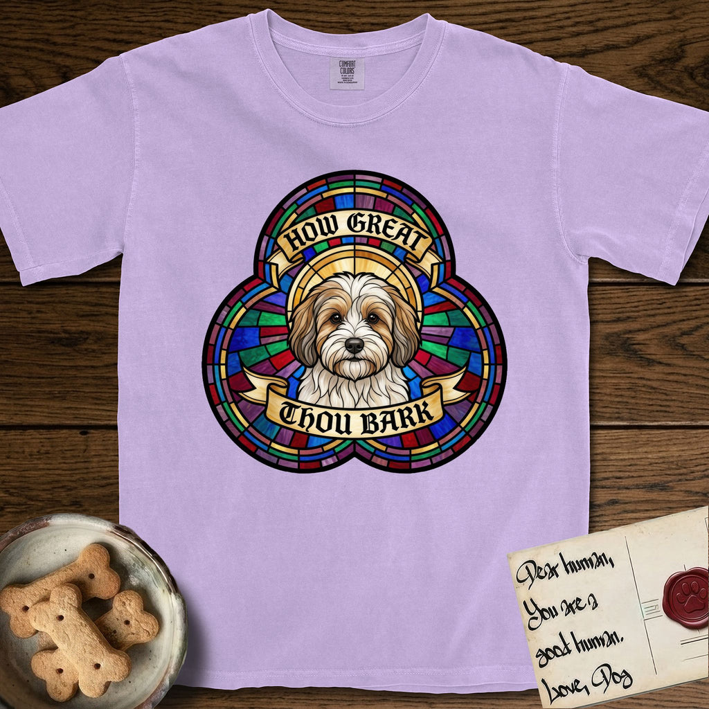 How Great Thou Bark Coton de Tulear T-Shirt flat lay in Orchid, featuring a full-color stained-glass saint window of a sable and white Coton de Tulear facing forward, haloed in golden light.