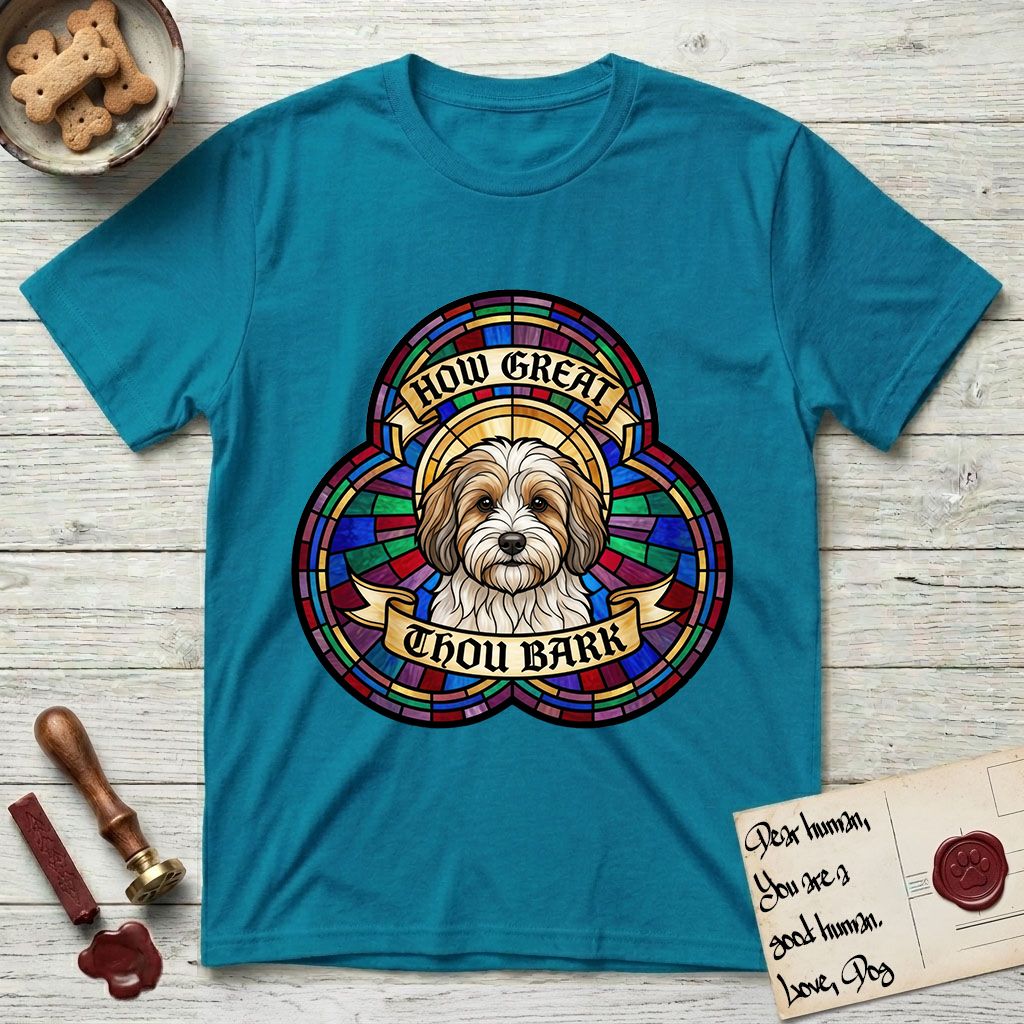 How Great Thou Bark Coton de Tulear T-Shirt flat lay in Tropical Blue, featuring a full-color stained-glass saint window of a sable and white Coton de Tulear facing forward, haloed in golden light.