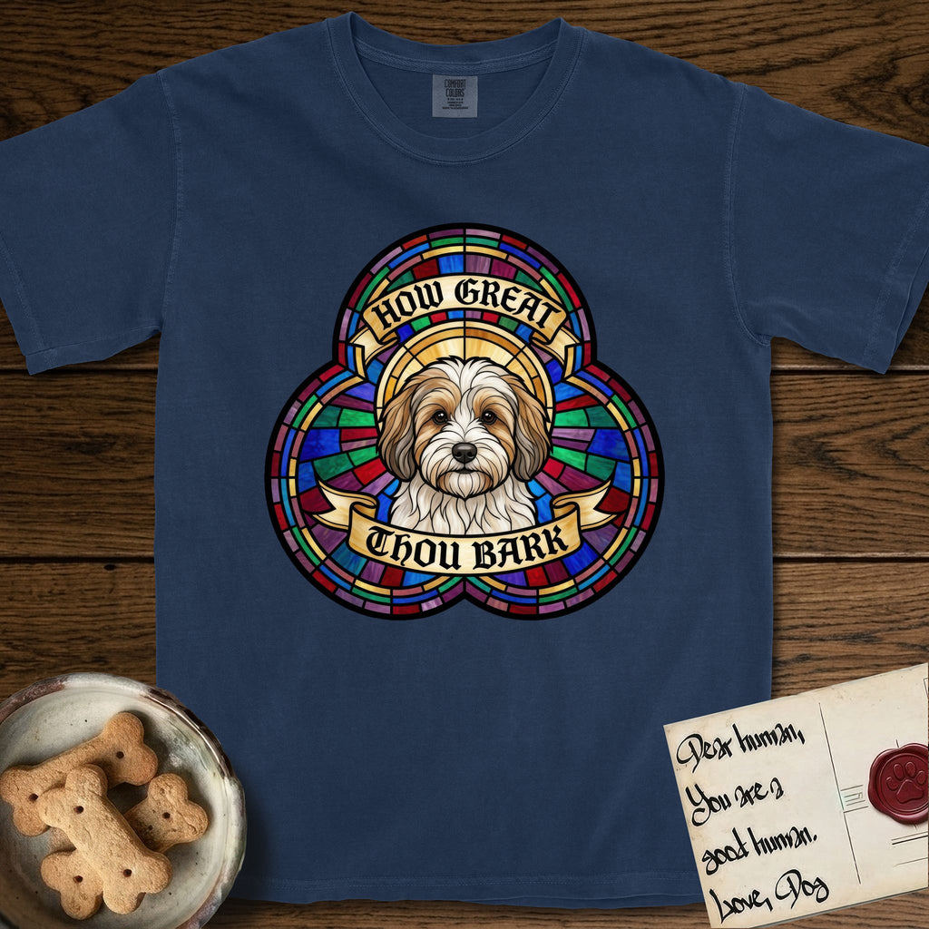 How Great Thou Bark Coton de Tulear T-Shirt flat lay in True Navy, featuring a full-color stained-glass saint window of a sable and white Coton de Tulear facing forward, haloed in golden light.