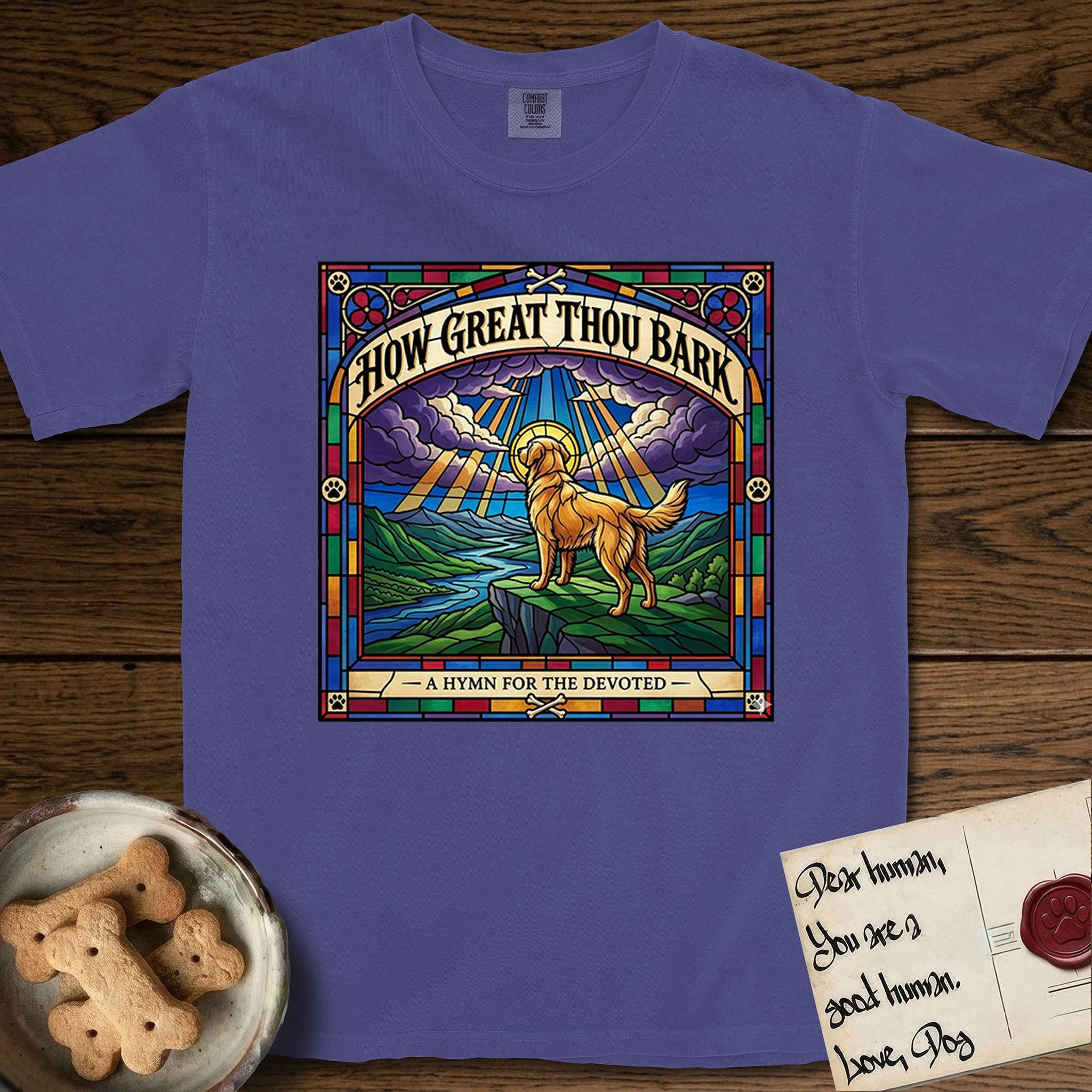 How Great Thou Bark Golden Retriever T-Shirt flat lay in Grape, featuring a full-color stained-glass saint window of a Golden Retriever standing on a mountain with light breaking through the clouds and a halo.