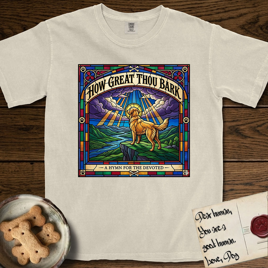 How Great Thou Bark Golden Retriever T-Shirt flat lay in Ivory, featuring a full-color stained-glass saint window of a Golden Retriever standing on a mountain with light breaking through the clouds and a halo.