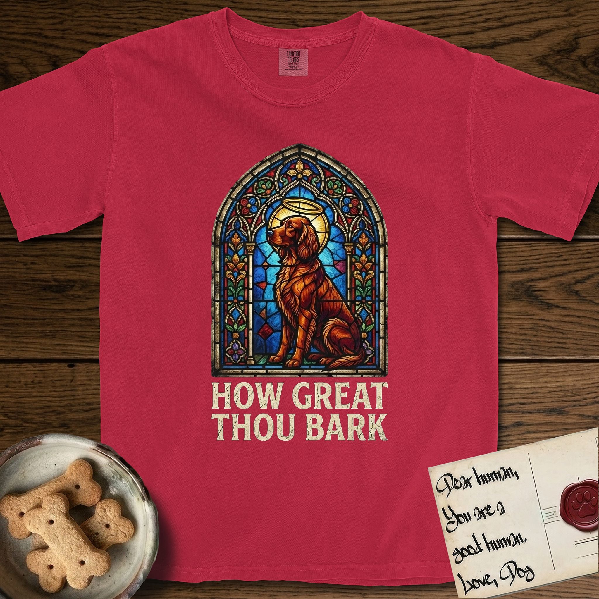 How Great Thou Bark Irish Setter T-Shirt flat lay in Red, featuring a full-color stained-glass saint window of an Irish Setter seated and gazing up into the light, with a halo.
