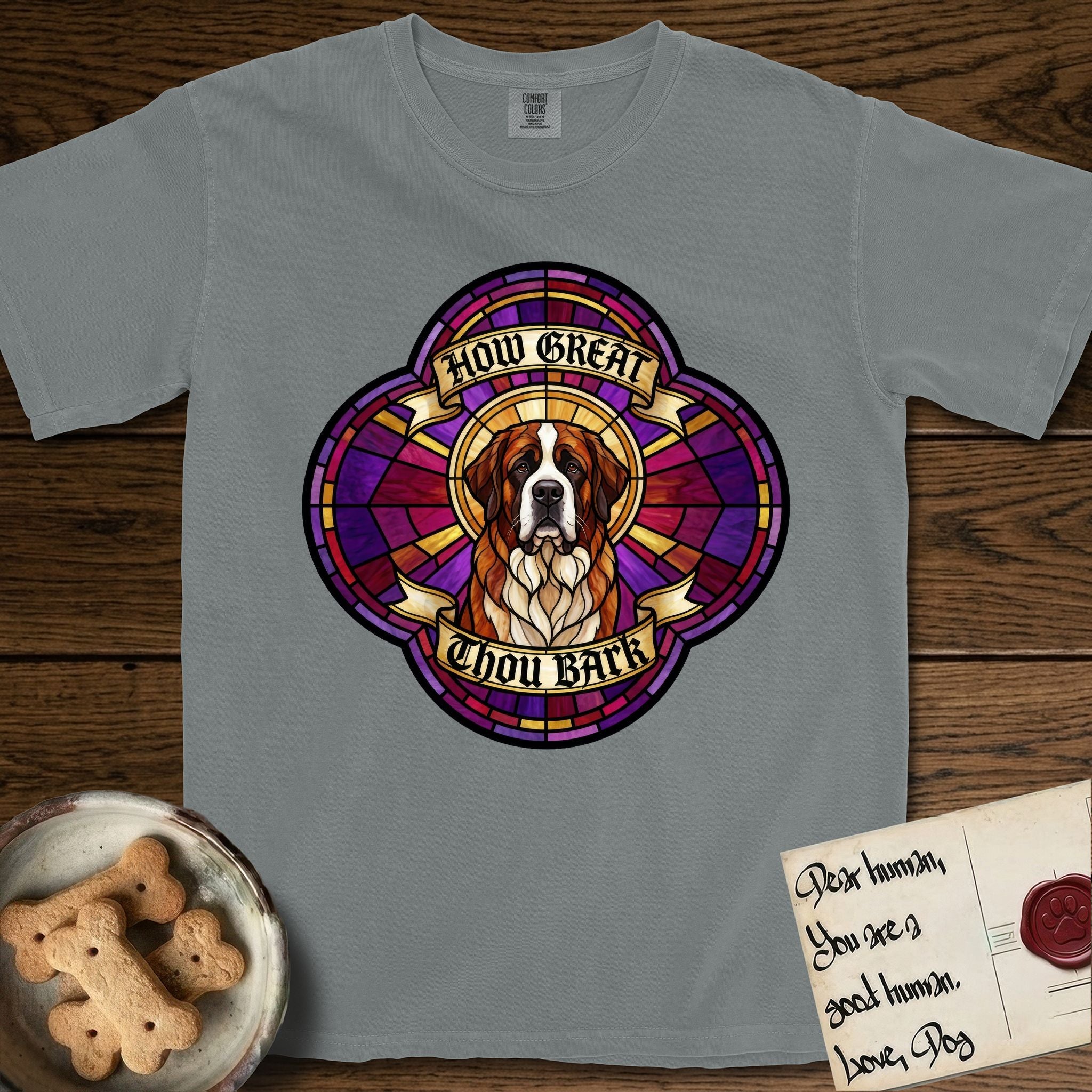 How Great Thou Bark Saint Bernard T-Shirt flat lay in Granite, featuring a full-color stained-glass saint window of a red and white Saint Bernard facing forward, haloed in golden light.