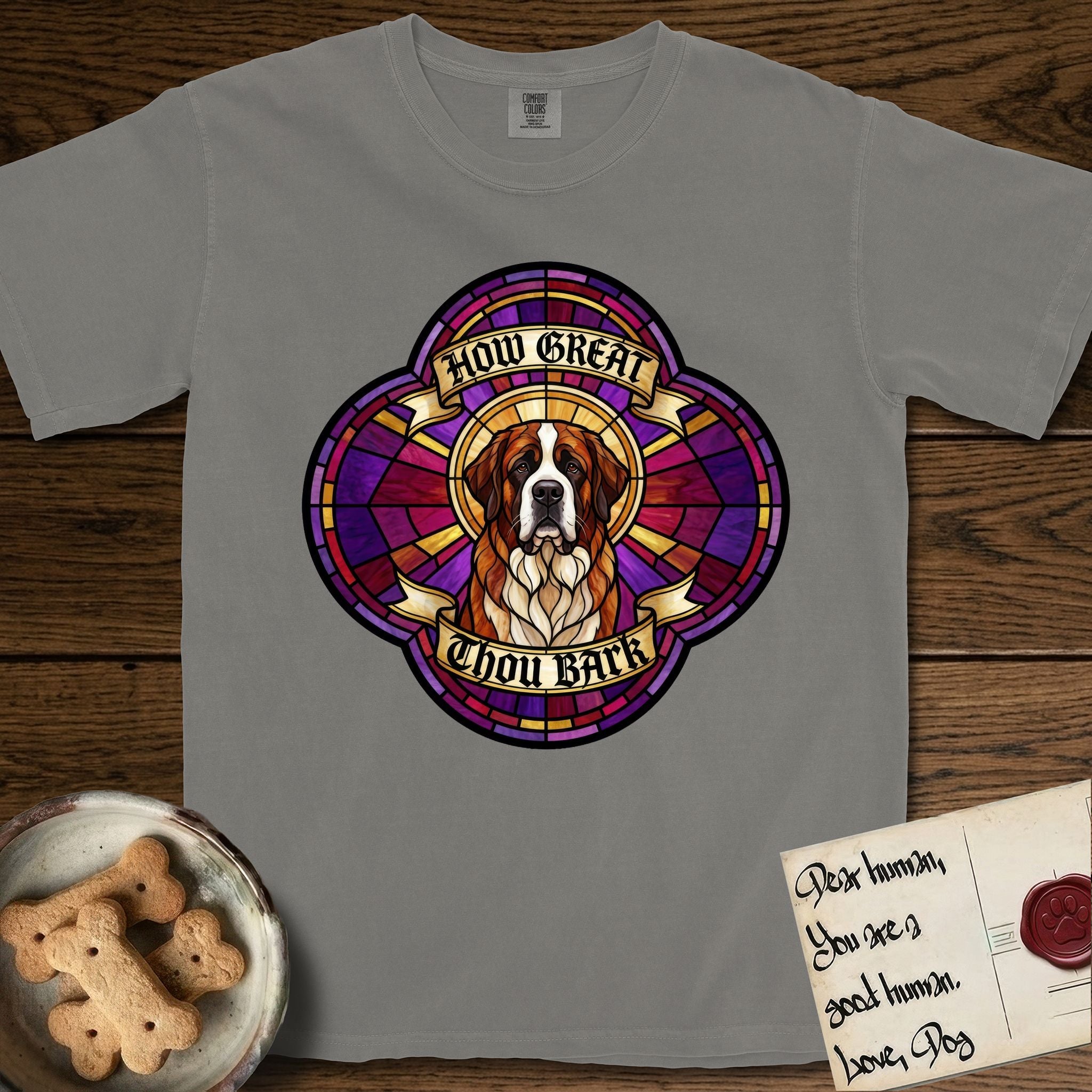 How Great Thou Bark Saint Bernard T-Shirt flat lay in Grey, featuring a full-color stained-glass saint window of a red and white Saint Bernard facing forward, haloed in golden light.
