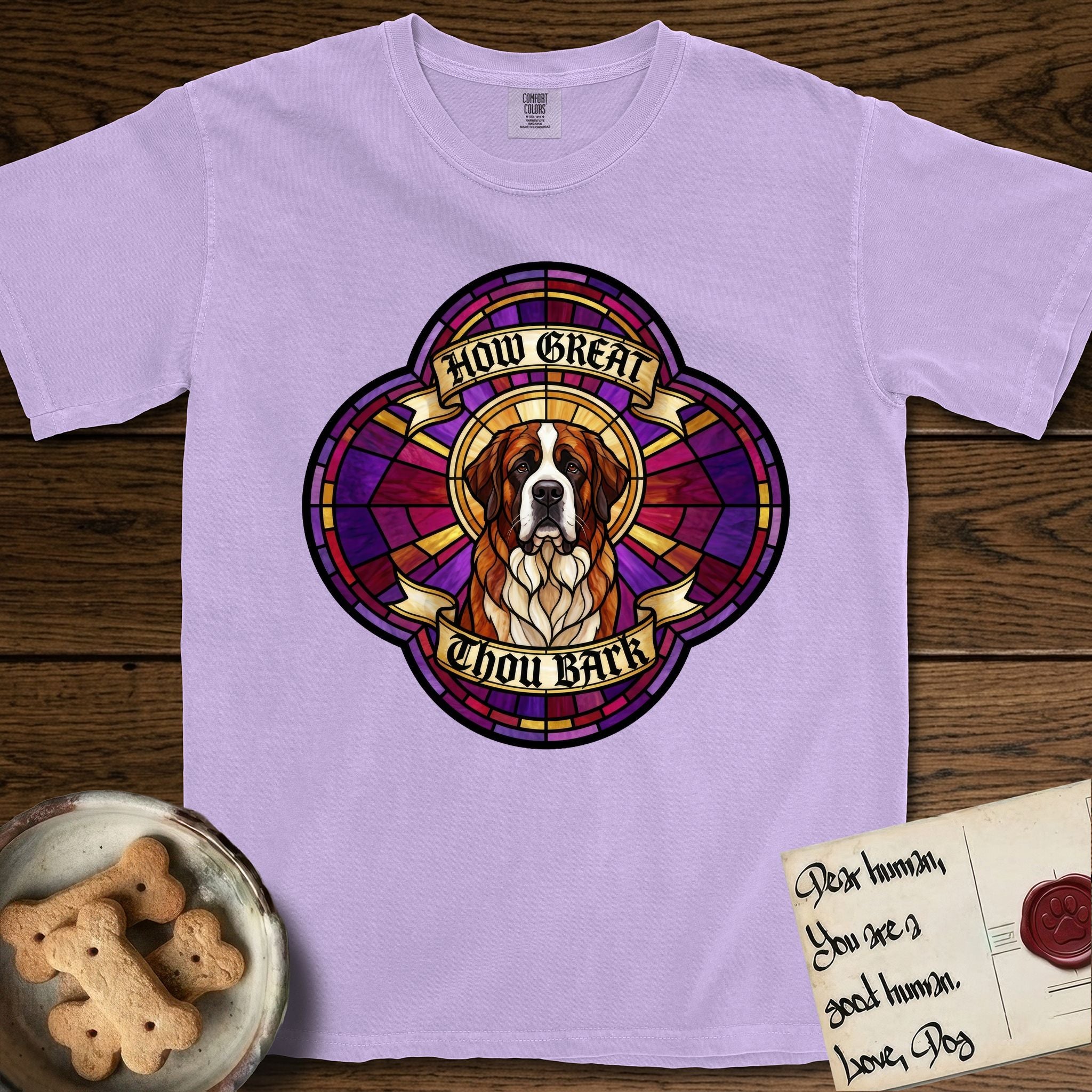 How Great Thou Bark Saint Bernard T-Shirt flat lay in Orchid, featuring a full-color stained-glass saint window of a red and white Saint Bernard facing forward, haloed in golden light.