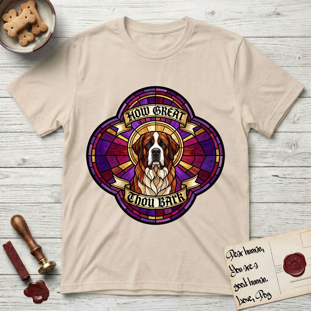 How Great Thou Bark Saint Bernard T-Shirt flat lay in Sand, featuring a full-color stained-glass saint window of a red and white Saint Bernard facing forward, haloed in golden light.