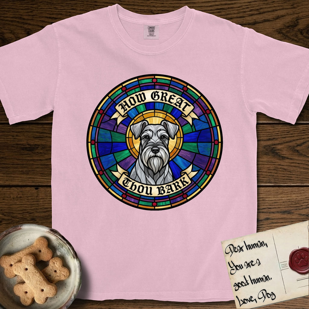 How Great Thou Bark Schnauzer T-Shirt flat lay in Blossom, featuring a full-color stained-glass saint window of a salt-and-pepper Schnauzer with bushy eyebrows and beard, haloed in golden light.