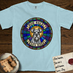 How Great Thou Bark Schnauzer T-Shirt flat lay in Chambray, featuring a full-color stained-glass saint window of a salt-and-pepper Schnauzer with bushy eyebrows and beard, haloed in golden light.