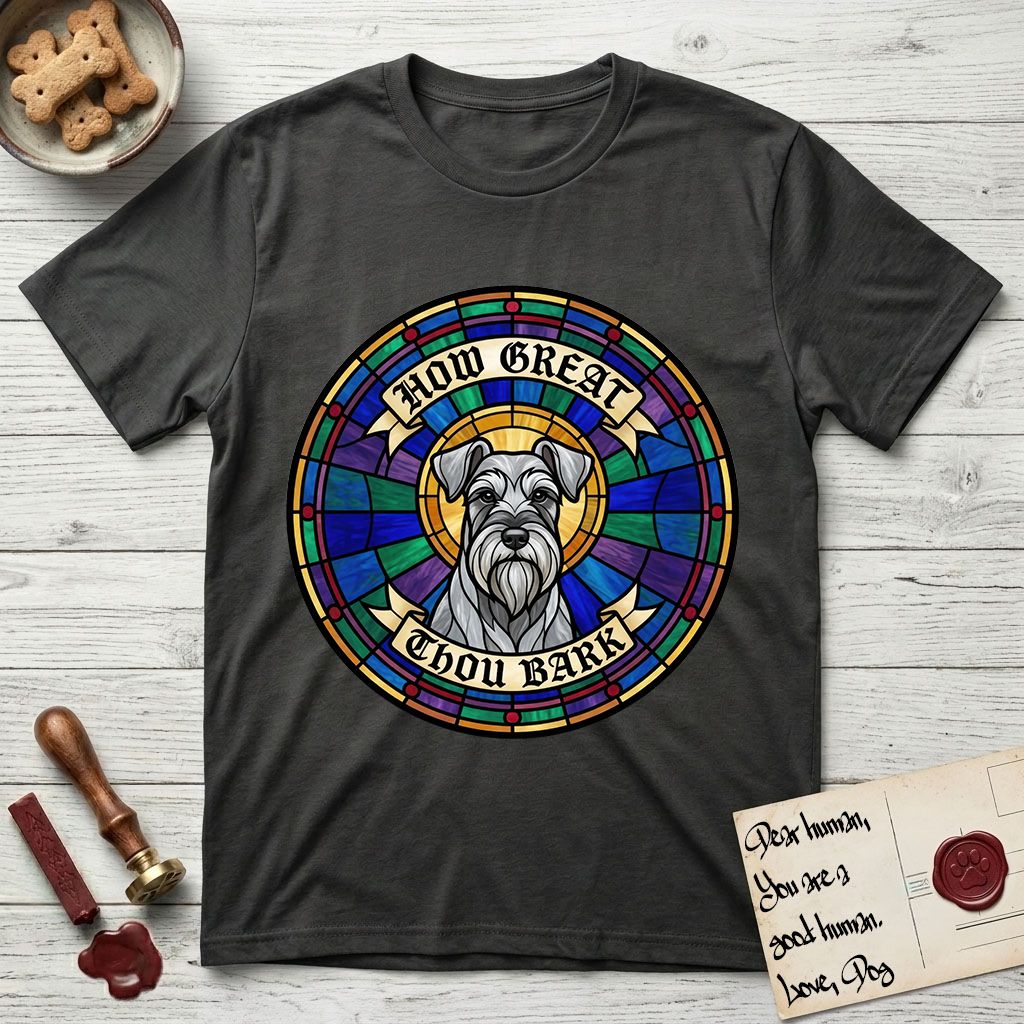 How Great Thou Bark Schnauzer T-Shirt flat lay in Charcoal, featuring a full-color stained-glass saint window of a salt-and-pepper Schnauzer with bushy eyebrows and beard, haloed in golden light.