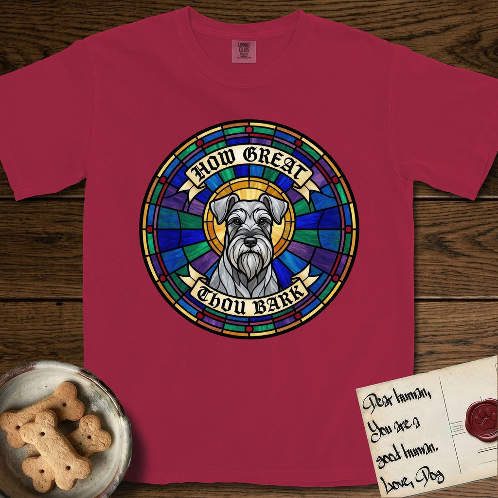 How Great Thou Bark Schnauzer T-Shirt flat lay in Chili, featuring a full-color stained-glass saint window of a salt-and-pepper Schnauzer with bushy eyebrows and beard, haloed in golden light.
