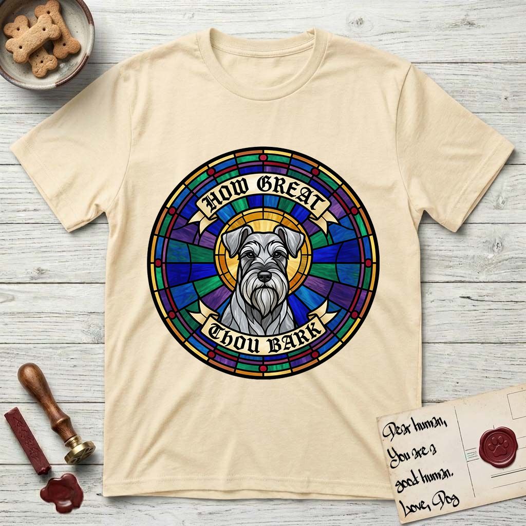How Great Thou Bark Schnauzer T-Shirt flat lay in Natural, featuring a full-color stained-glass saint window of a salt-and-pepper Schnauzer with bushy eyebrows and beard, haloed in golden light.