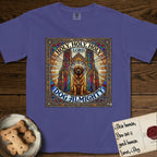 Holy Holy Holy Newfoundland T-Shirt flat lay in Grape, featuring a gothic stained-glass window in jewel tones with a Newfoundland at center, Celtic knotwork border, corner paw prints, and the words Holy Holy Holy and Dog Almighty.