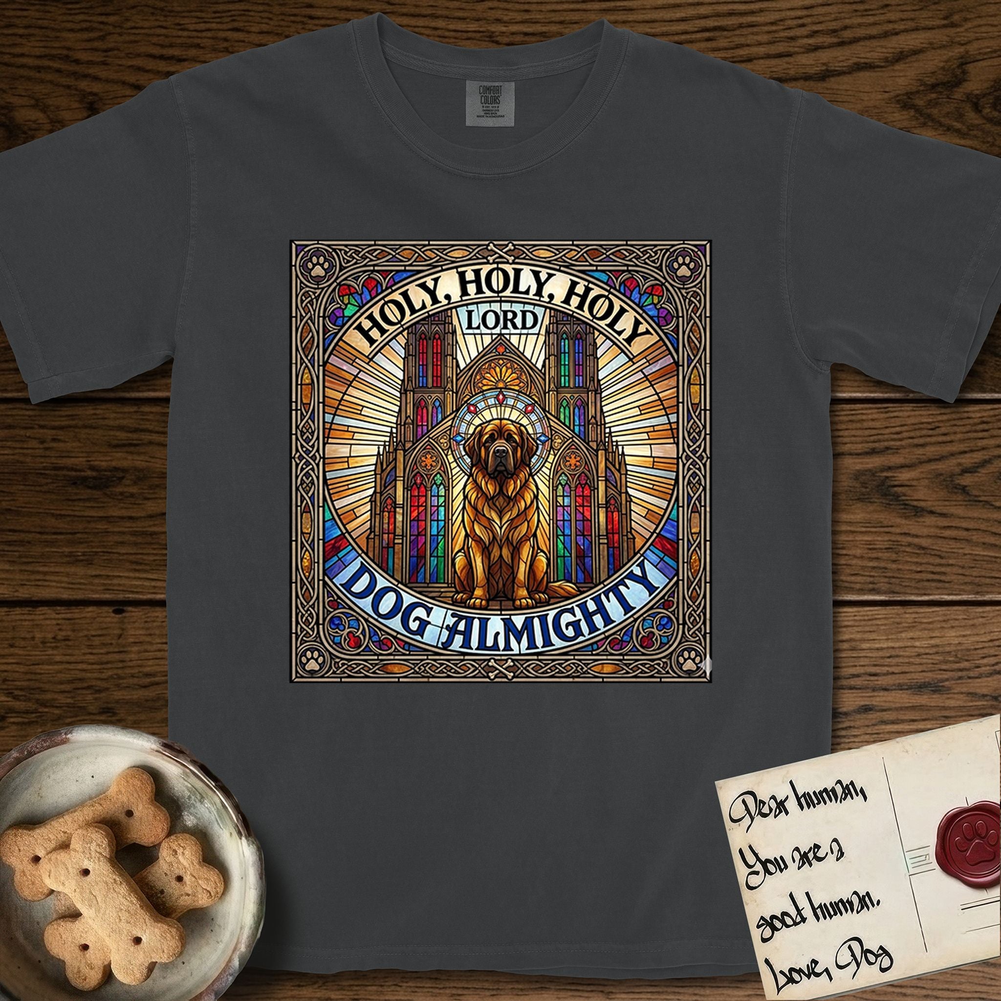 Holy Holy Holy Newfoundland T-Shirt flat lay in Graphite, featuring a gothic stained-glass window in jewel tones with a Newfoundland at center, Celtic knotwork border, corner paw prints, and the words Holy Holy Holy and Dog Almighty.