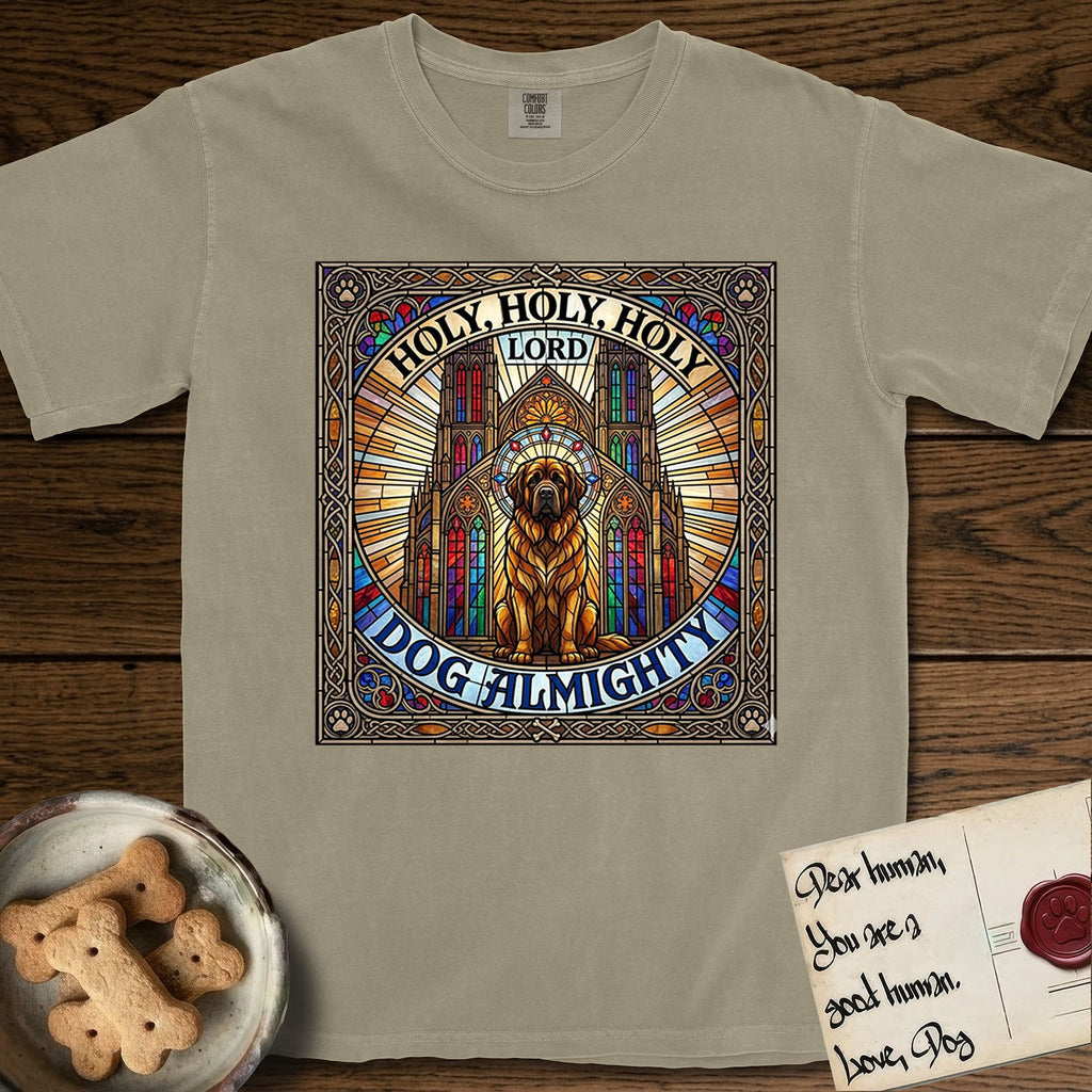 Holy Holy Holy Newfoundland T-Shirt flat lay in Khaki, featuring a gothic stained-glass window in jewel tones with a Newfoundland at center, Celtic knotwork border, corner paw prints, and the words Holy Holy Holy and Dog Almighty.
