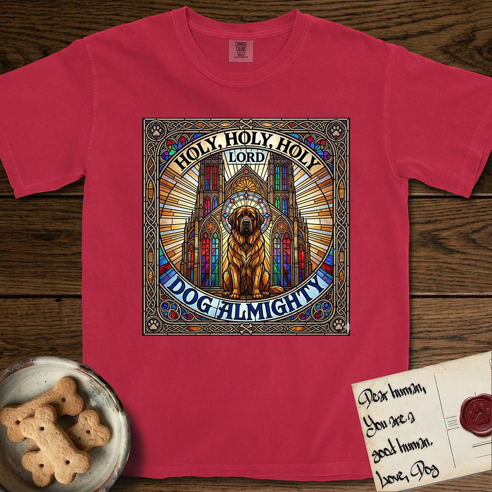 Holy Holy Holy Newfoundland T-Shirt flat lay in Red, featuring a gothic stained-glass window in jewel tones with a Newfoundland at center, Celtic knotwork border, corner paw prints, and the words Holy Holy Holy and Dog Almighty.