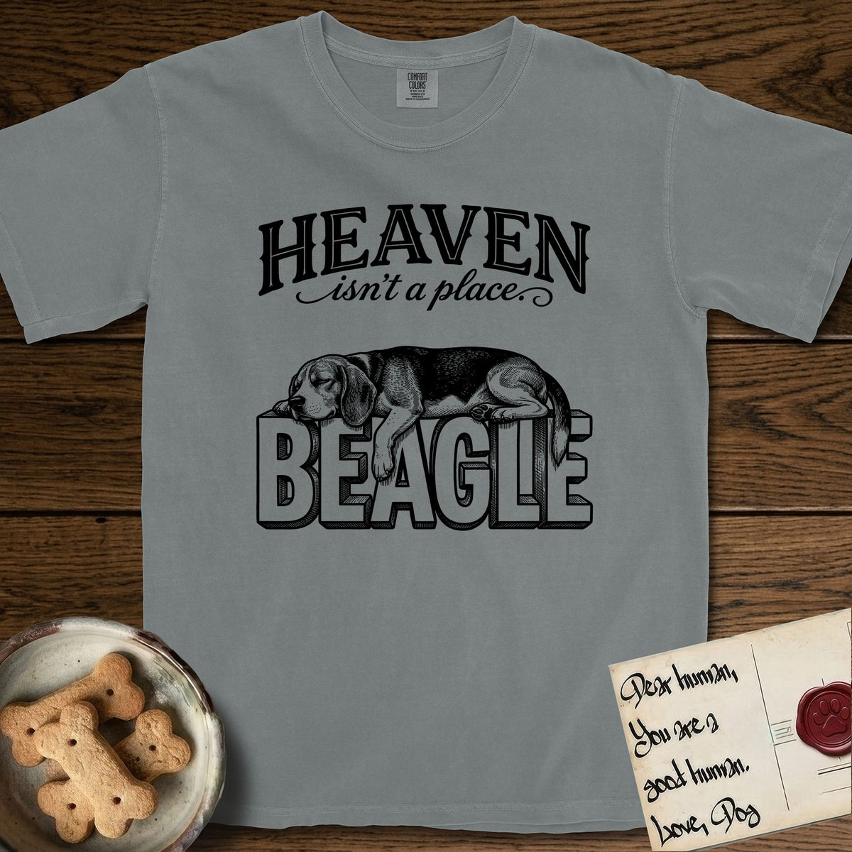 Heaven Isn't a Place Beagle T-Shirt flat lay in Granite, featuring Black ink engraving illustration of a tricolor Beagle asleep on top of the giant carved block letters BEAGLE, under the lettering HEAVEN isn't a place..