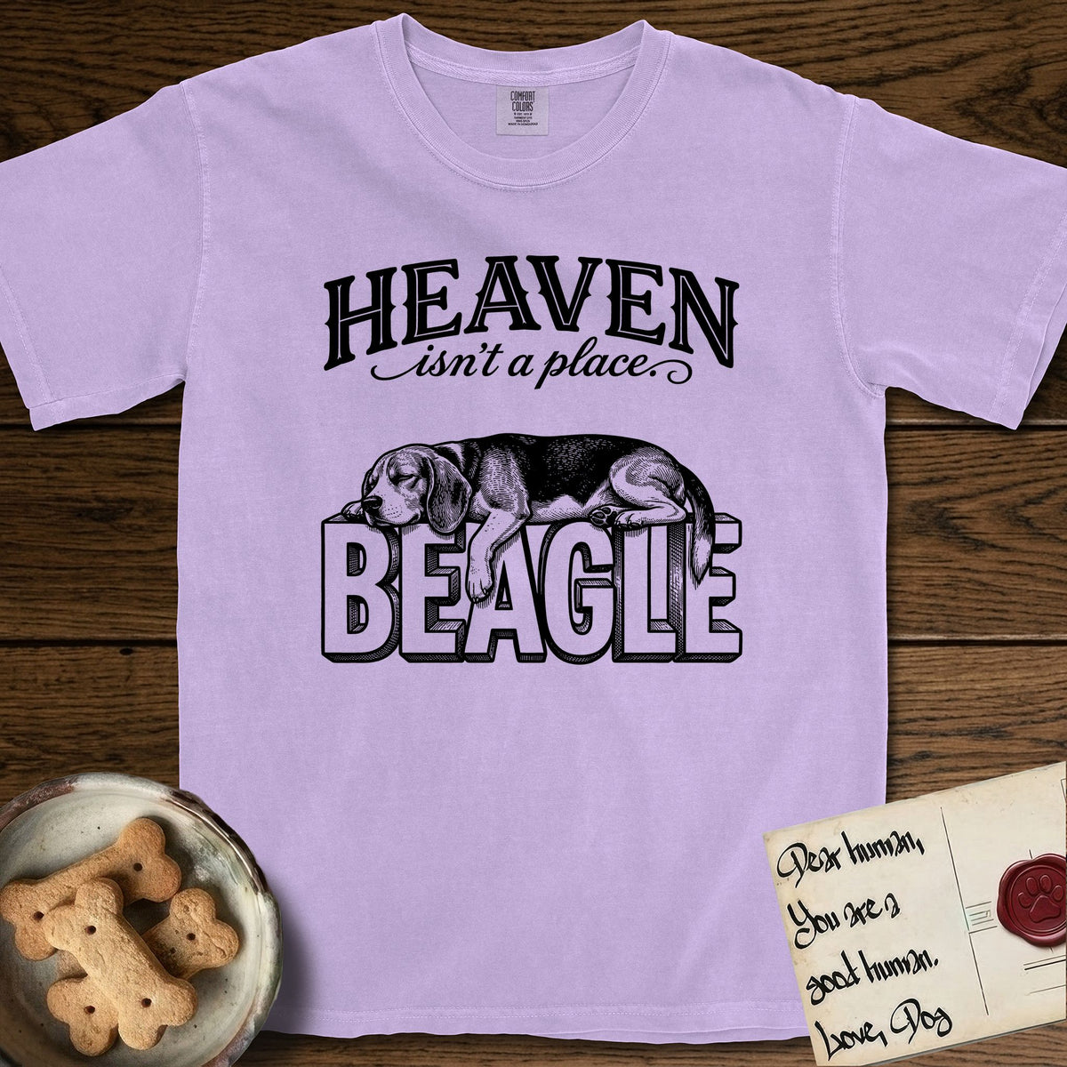 Heaven Isn't a Place Beagle T-Shirt flat lay in Orchid, featuring Black ink engraving illustration of a tricolor Beagle asleep on top of the giant carved block letters BEAGLE, under the lettering HEAVEN isn't a place..