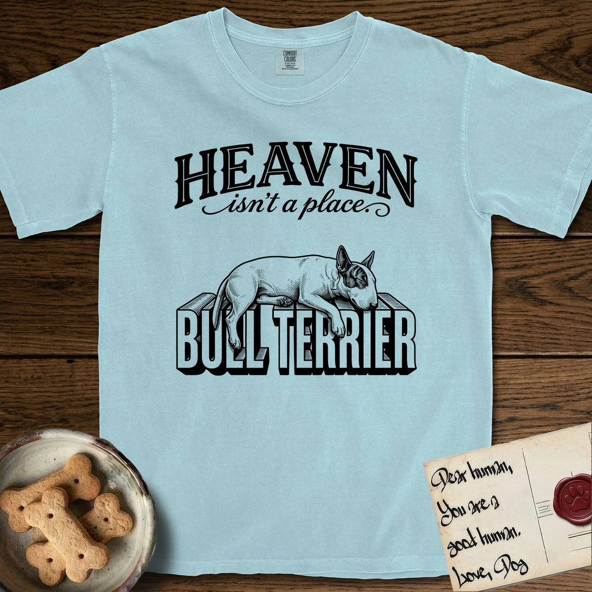 Heaven Isn't a Place Bull Terrier T-Shirt flat lay in Chambray, featuring Black ink engraving illustration of a Bull Terrier with a dark patch over one eye asleep on top of the giant carved block letters BULL TERRIER, under the lettering HEAVEN isn't a place..