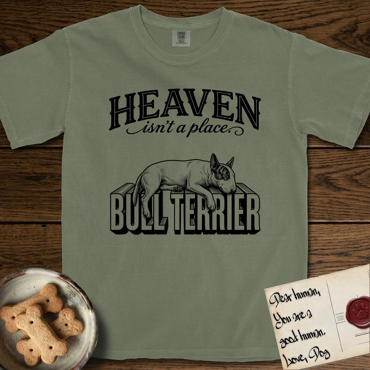 Heaven Isn't a Place Bull Terrier T-Shirt flat lay in Sage, featuring Black ink engraving illustration of a Bull Terrier with a dark patch over one eye asleep on top of the giant carved block letters BULL TERRIER, under the lettering HEAVEN isn't a place..