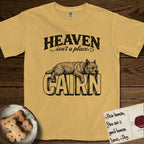 Heaven Isn't a Place Cairn Terrier T-Shirt flat lay in Mustard, featuring Black ink engraving illustration of a shaggy Cairn Terrier asleep on top of the giant carved block letters CAIRN, under the lettering HEAVEN isn't a place..