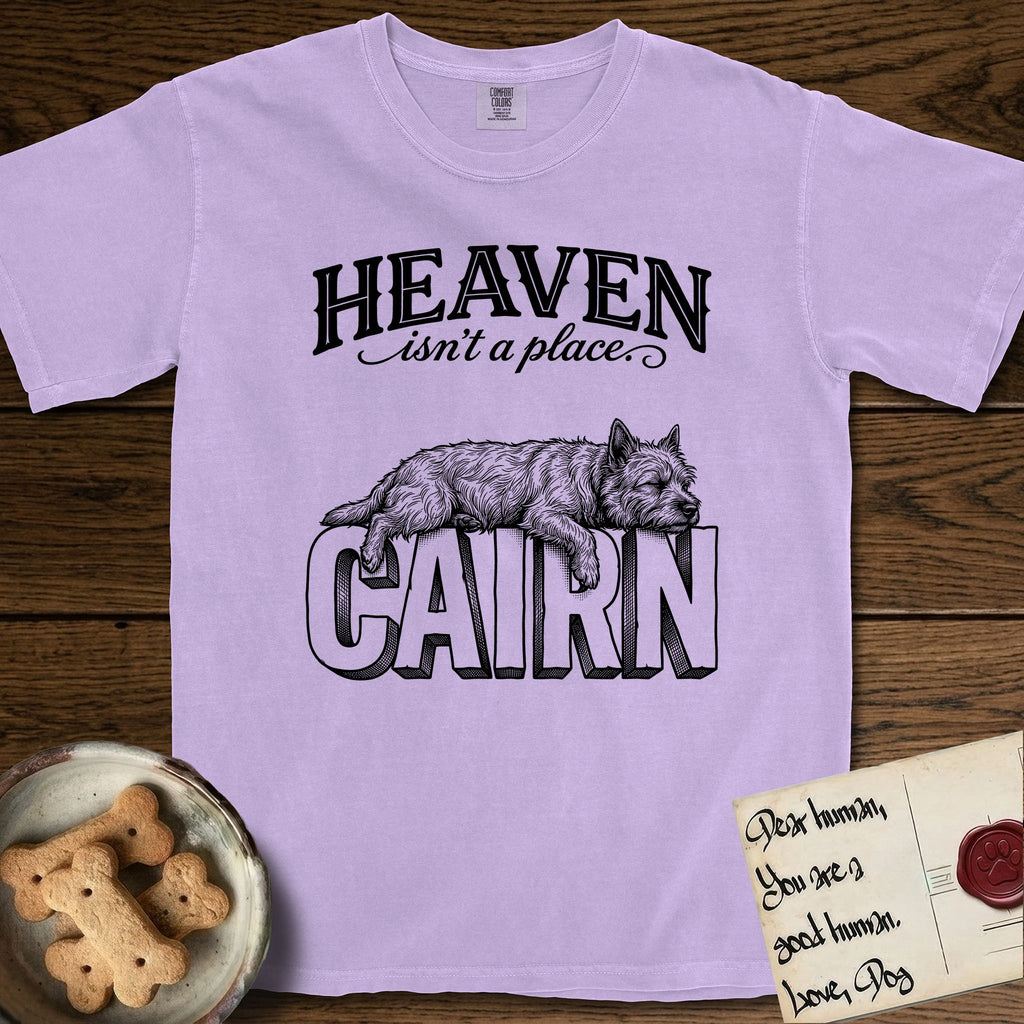 Heaven Isn't a Place Cairn Terrier T-Shirt flat lay in Orchid, featuring Black ink engraving illustration of a shaggy Cairn Terrier asleep on top of the giant carved block letters CAIRN, under the lettering HEAVEN isn't a place..