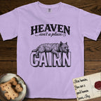 Heaven Isn't a Place Cairn Terrier T-Shirt flat lay in Orchid, featuring Black ink engraving illustration of a shaggy Cairn Terrier asleep on top of the giant carved block letters CAIRN, under the lettering HEAVEN isn't a place..