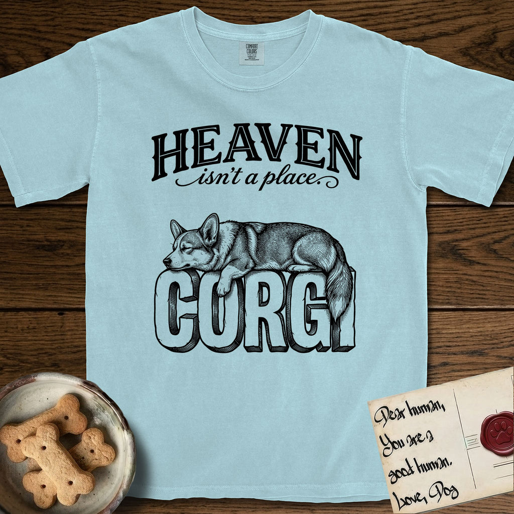 Heaven Isn't a Place Corgi T-Shirt flat lay in Chambray, featuring Black ink engraving illustration of a Corgi with a long fluffy tail asleep on top of the giant carved block letters CORGI, under the lettering HEAVEN isn't a place..
