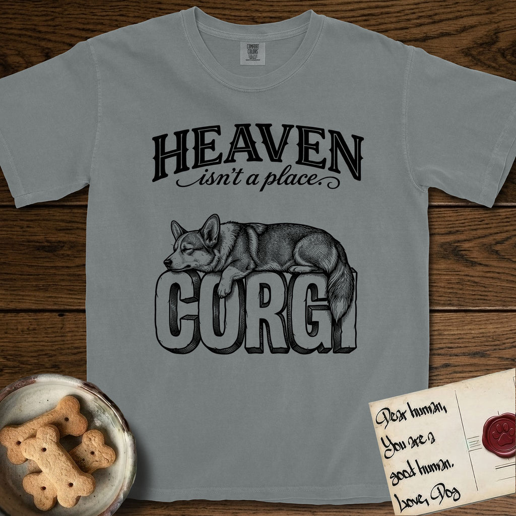 Heaven Isn't a Place Corgi T-Shirt flat lay in Granite, featuring Black ink engraving illustration of a Corgi with a long fluffy tail asleep on top of the giant carved block letters CORGI, under the lettering HEAVEN isn't a place..