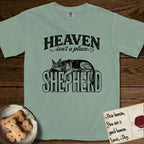 Heaven Isn't a Place German Shepherd T-Shirt flat lay in Bay, featuring Black ink engraving illustration of a German Shepherd asleep on top of the giant carved block letters SHEPHERD, under the lettering HEAVEN isn't a place..