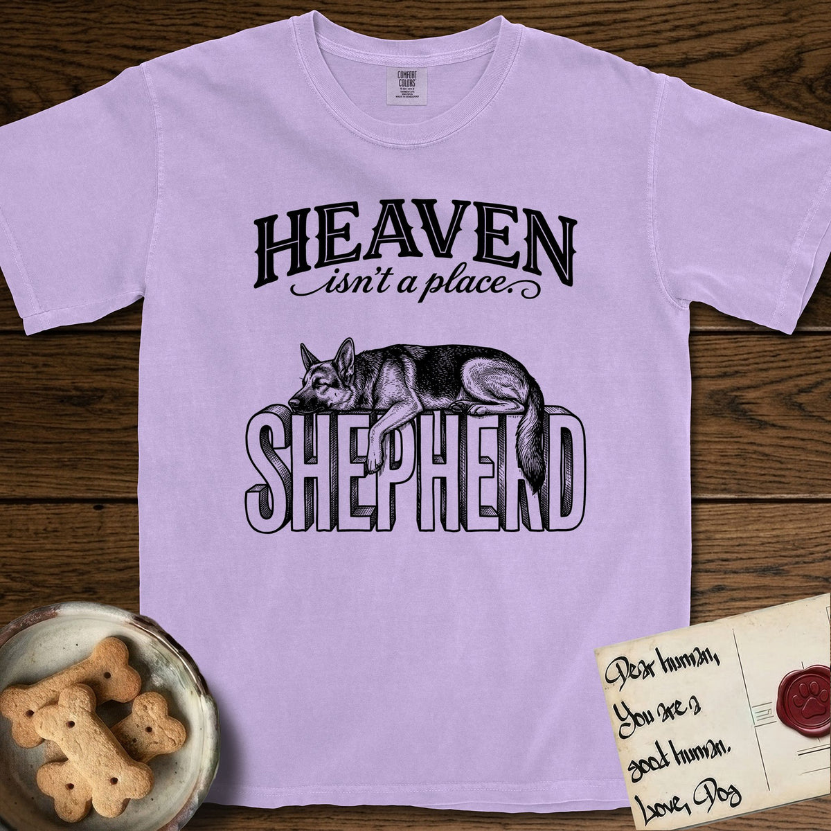 Heaven Isn't a Place German Shepherd T-Shirt flat lay in Orchid, featuring Black ink engraving illustration of a German Shepherd asleep on top of the giant carved block letters SHEPHERD, under the lettering HEAVEN isn't a place..