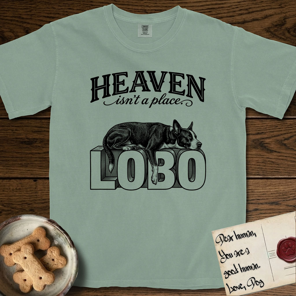 Heaven Isn't a Place Lobo T-Shirt flat lay in Bay, featuring Black ink engraving illustration of Lobo, a black-and-white Cattle Dog and Pitbull mix with a white blaze, asleep on top of the giant carved block letters LOBO, under the lettering HEAVEN isn't a place..