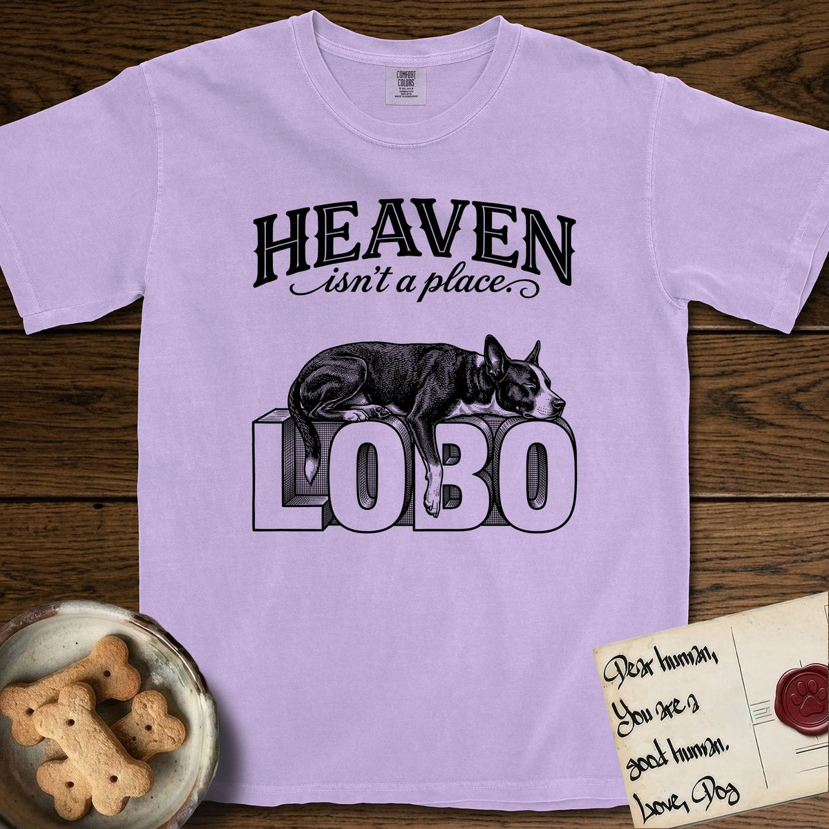 Heaven Isn't a Place Lobo T-Shirt flat lay in Orchid, featuring Black ink engraving illustration of Lobo, a black-and-white Cattle Dog and Pitbull mix with a white blaze, asleep on top of the giant carved block letters LOBO, under the lettering HEAVEN isn't a place..