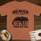 Heaven Isn't a Place Newfoundland T-Shirt flat lay in Yam, featuring Black ink engraving illustration of a Newfoundland asleep on top of the giant carved block letters NEWFIE, under the lettering HEAVEN isn't a place..