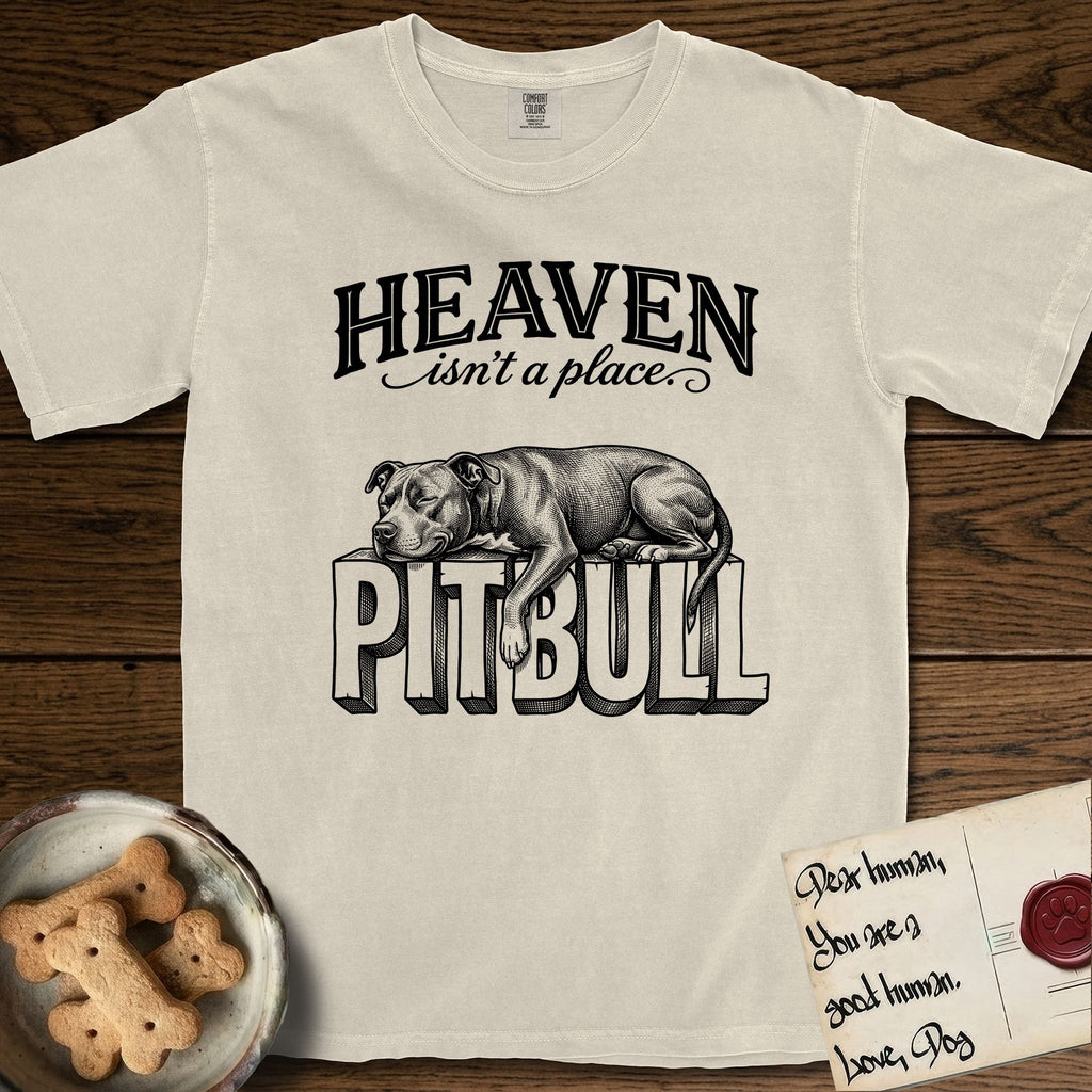 Heaven Isn't a Place Pitbull T-Shirt flat lay in Ivory, featuring Black ink engraving illustration of a Pitbull asleep on top of the giant carved block letters PITBULL, under the lettering HEAVEN isn't a place..