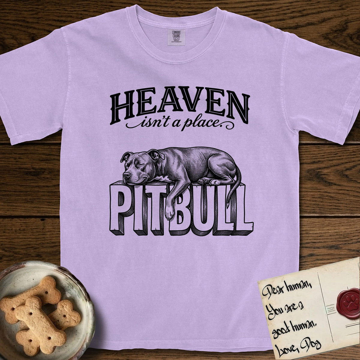 Heaven Isn't a Place Pitbull T-Shirt flat lay in Orchid, featuring Black ink engraving illustration of a Pitbull asleep on top of the giant carved block letters PITBULL, under the lettering HEAVEN isn't a place..