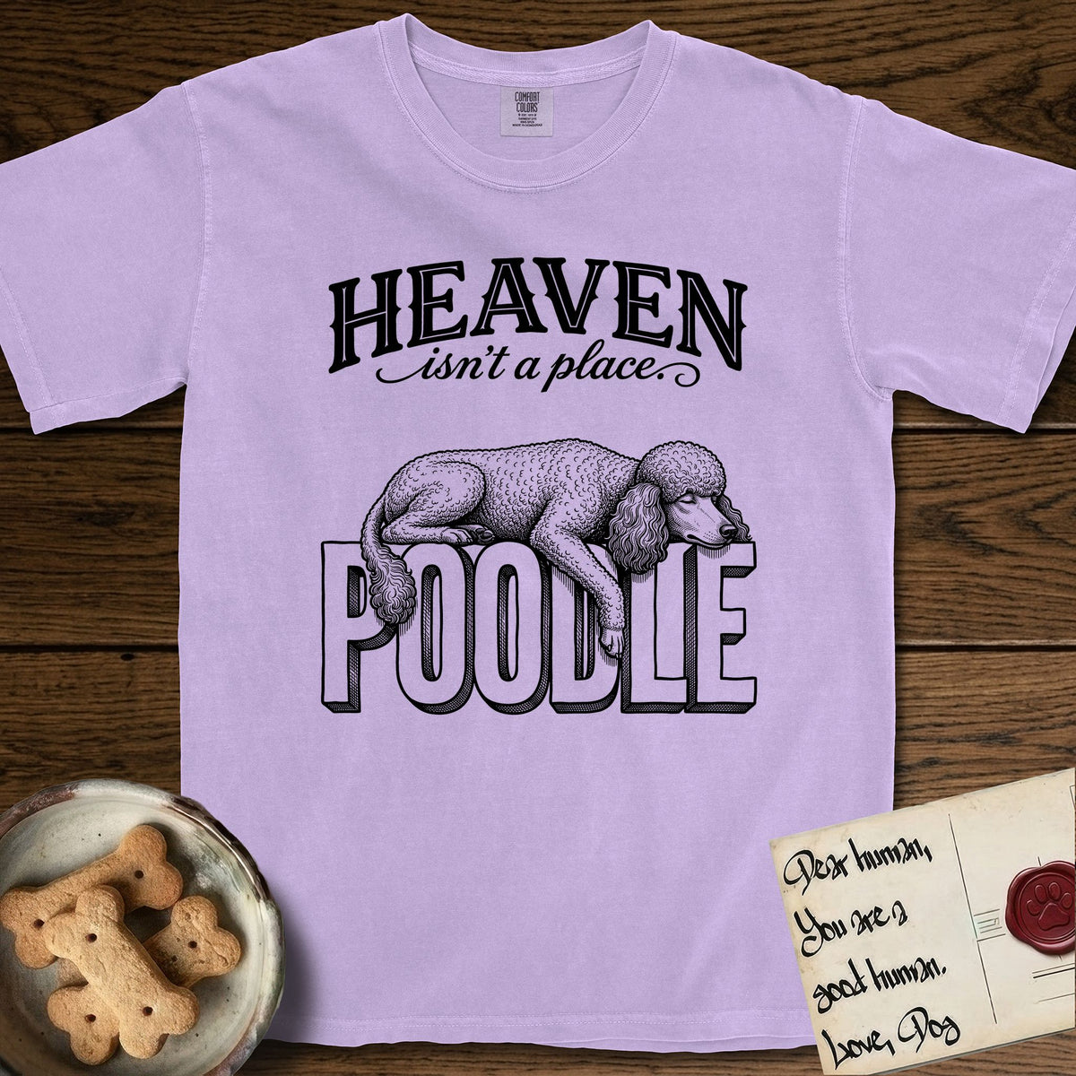 Heaven Isn't a Place Poodle T-Shirt flat lay in Orchid, featuring Black ink engraving illustration of a curly Standard Poodle asleep on top of the giant carved block letters POODLE, under the lettering HEAVEN isn't a place..