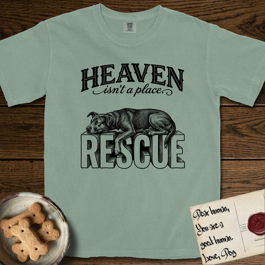 Heaven Isn't a Place Rescue Mutt T-Shirt flat lay in Bay, featuring Black ink engraving illustration of a rescue Dog that is a Lab, Shepherd and Pitbull mix asleep on top of the giant carved block letters RESCUE, under the lettering HEAVEN isn't a place..
