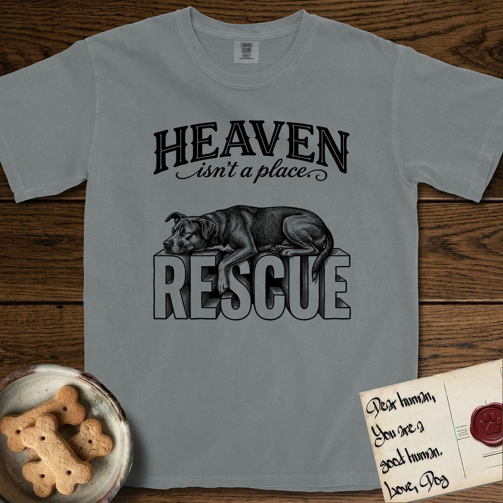 Heaven Isn't a Place Rescue Mutt T-Shirt flat lay in Granite, featuring Black ink engraving illustration of a rescue Dog that is a Lab, Shepherd and Pitbull mix asleep on top of the giant carved block letters RESCUE, under the lettering HEAVEN isn't a place..