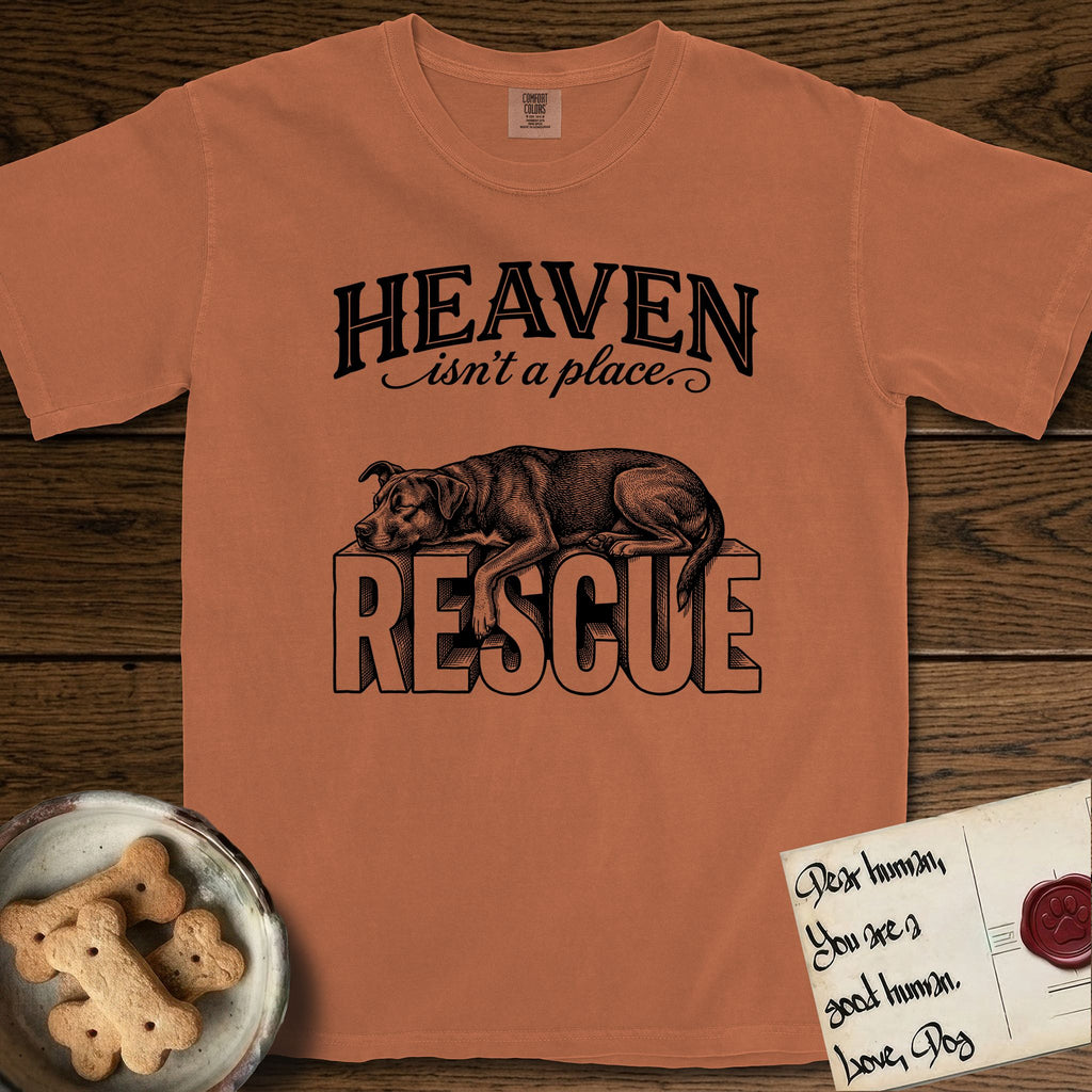 Heaven Isn't a Place Rescue Mutt T-Shirt flat lay in Yam, featuring Black ink engraving illustration of a rescue Dog that is a Lab, Shepherd and Pitbull mix asleep on top of the giant carved block letters RESCUE, under the lettering HEAVEN isn't a place..